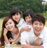 부모와 자녀 두명의 4인구성의 가족이 행복하게 미소짓는 사진